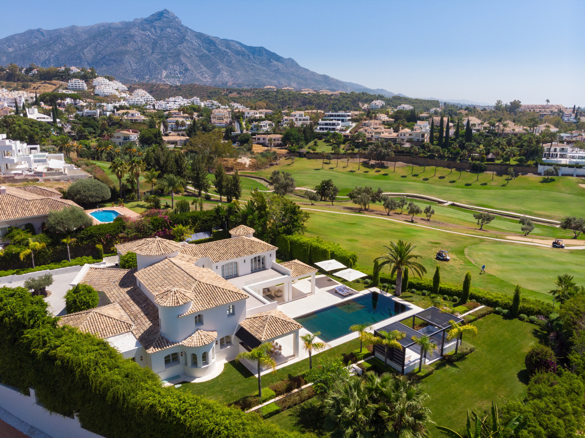 Aerial view of a luxury villa overlooking a golf course with mountain backdrop